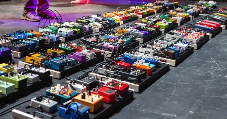 Pedalera de guitarra con numerosos efectos organizados en una cadena de señal sobre un escenario.
