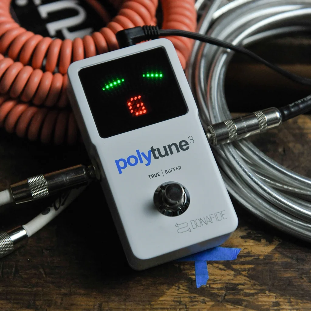 Afinador de pedal TC Electronic PolyTune conectado mediante cables de instrumento.