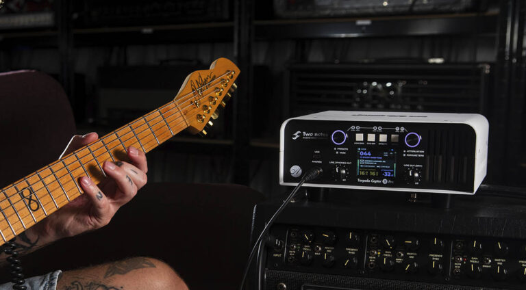 Two Notes Torpedo Captor X Pro: análisis de la load box más completa de la marca 12 Unidad de carga reactiva y simulación de pantalla Two Notes Torpedo Captor X Pro conectada a un amplificador de guitarra, junto a una guitarra eléctrica, mostrando su pantalla digital y controles de modelado de sonido en un entorno de estudio.