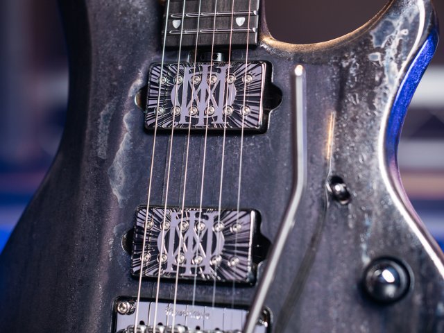 Ernie Ball Music Man Majesty BFR 2026: análisis de la nueva colección limitada de John Petrucci 8 Detalle del cuerpo de la Ernie Ball Music Man Majesty BFR 2026 Lost in Space, mostrando el acabado metalizado de inspiración espacial en tonos gris oscuro y plateado, las dos pastillas humbucker DiMarzio personalizadas con grabado Majesty, el puente vibrato Music Man y los controles integrados en el diseño ergonómico del instrumento.