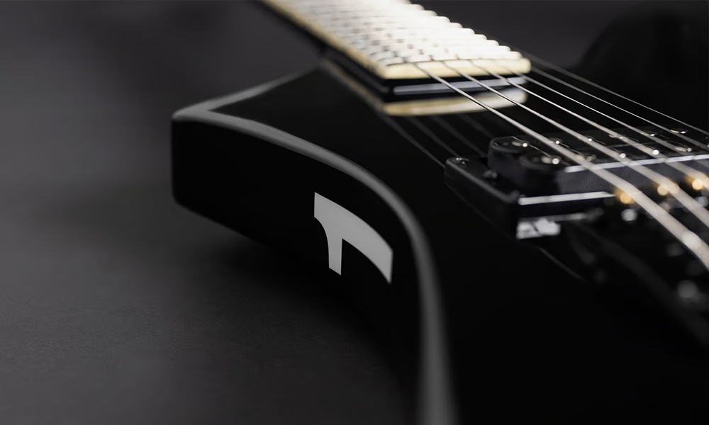 Jackson Legend Series: análisis de las reediciones limitadas de Randy Rhoads, Scott Ian, Marty Friedman y David Ellefson 8 Detalle del cuerpo de la guitarra Jackson Legend Series Limited Edition Signature Marty Friedman Kelly KE-1, mostrando el acabado negro brillante, el característico gráfico blanco inspirado en la bandera japonesa sobre el lateral del cuerpo, el puente fijo de cuerdas a través del cuerpo y la pastilla humbucker Seymour Duncan en posición de puente.