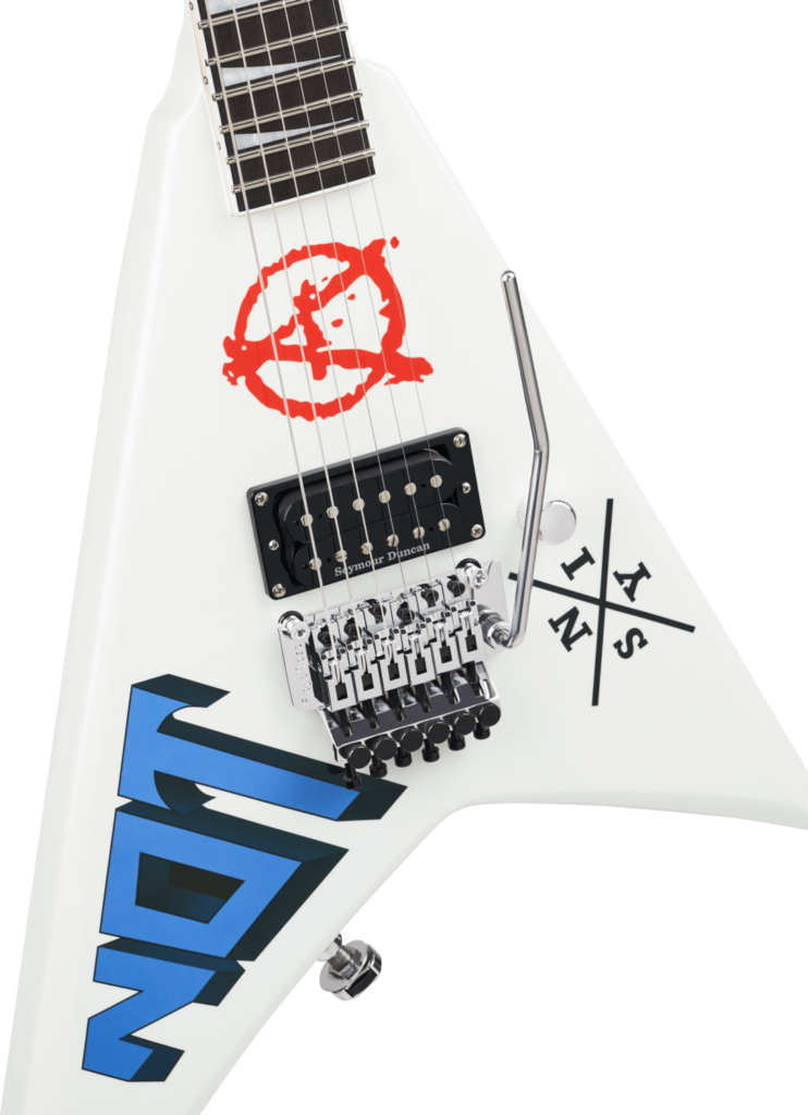 Jackson Legend Series: análisis de las reediciones limitadas de Randy Rhoads, Scott Ian, Marty Friedman y David Ellefson 12 Detalle del cuerpo de la guitarra Jackson Legend Series Limited Edition Signature Scott Ian Rhoads RR22, mostrando la pastilla humbucker Seymour Duncan, puente Floyd Rose cromado, palanca de vibrato y los gráficos personalizados “NOT”, el símbolo anarquista de Anthrax y el emblema “S.I.N.Y.” sobre el acabado blanco.