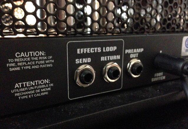 Guía indispensable de pedales de guitarra (II): pedales en el loop de efectos del amplificador 2 Panel trasero de un amplificador de guitarra con conexiones de bucle de efectos (Effects Loop) Send y Return, salida de previo (Preamp Out) y advertencias de seguridad impresas en el chasis metálico.