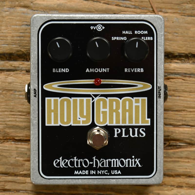 Guía indispensable de pedales de guitarra (II): pedales en el loop de efectos del amplificador 6 Pedal de reverb Electro-Harmonix Holy Grail Plus con acabado metálico plateado, tres controles de ajuste para mezcla, cantidad y tipo de reverberación, e interruptor de activación central sobre una superficie de madera envejecida.