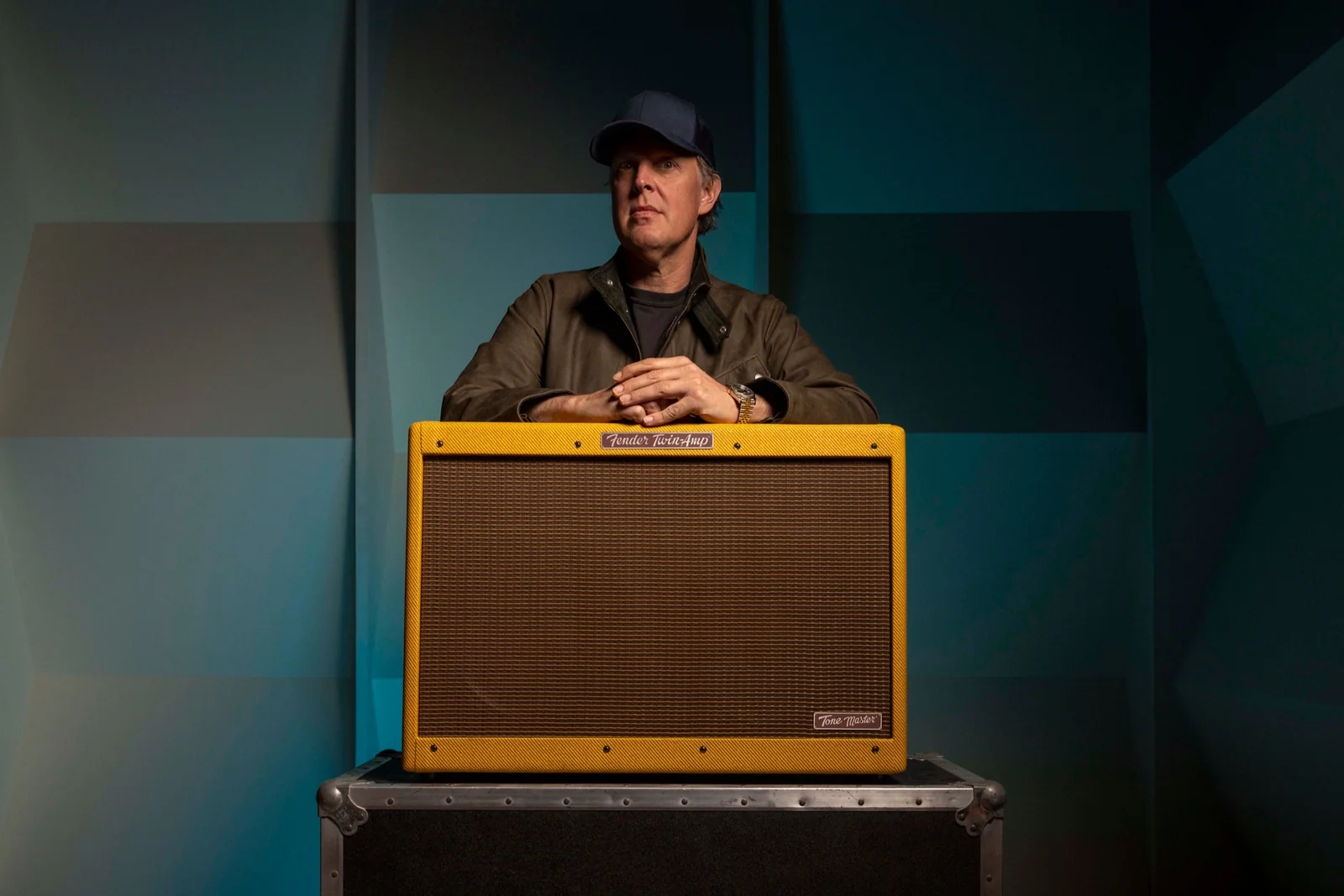 Amplificador Fender Tone Master '59 Twin Reverb JB Edition colocado sobre un flight case, con Joe Bonamassa apoyado detrás del equipo en un entorno de estudio, destacando el diseño clásico con acabado tweed y rejilla frontal de gran tamaño.