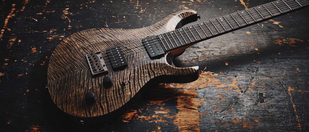 Detalle de la PRS Tekton SVN de siete cuerdas en acabado Black Tourmaline, mostrando la tapa de arce flameado con vetas marcadas, puente fijo, configuración de doble humbucker, diapasón de amplio rango para siete cuerdas y diseño ergonómico orientado a afinaciones graves y estilos modernos de alta ganancia.