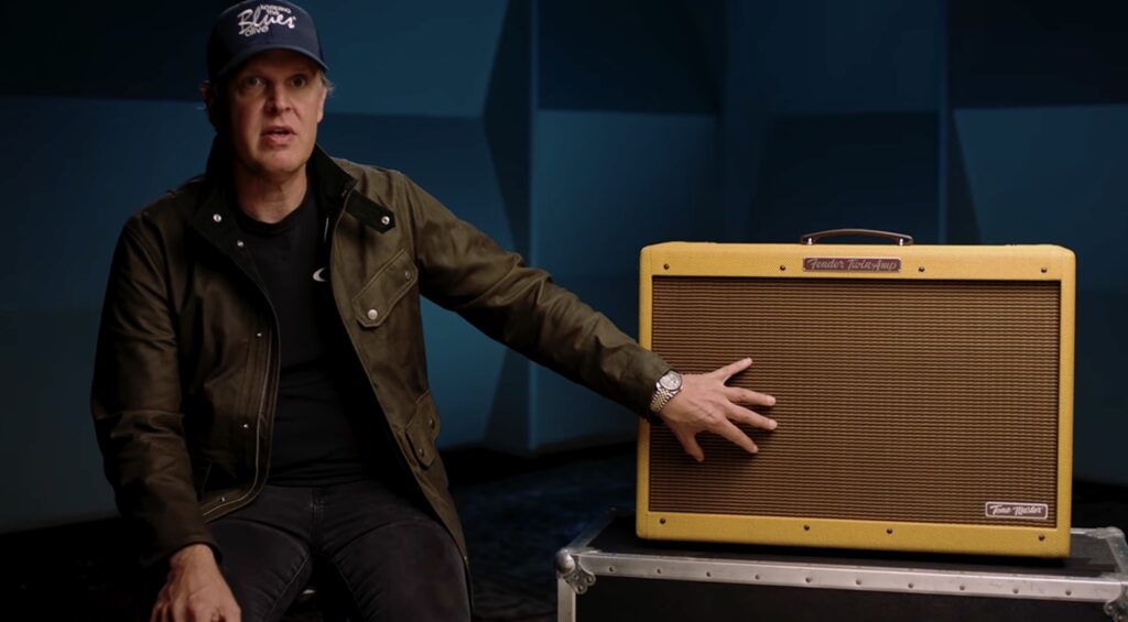 Fender Tone Master 59 Twin JB: análisis del primer amplificador digital firmado por Bonamassa 2 Joe Bonamassa sentado junto al amplificador Fender Tone Master '59 Twin Reverb JB Edition con acabado tweed, señalando la rejilla frontal del equipo durante una presentación o demostración del modelo en un entorno de estudio.